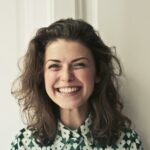 Portrait of a joyful brunette woman with a vibrant smile indoors, capturing happiness and positivity.